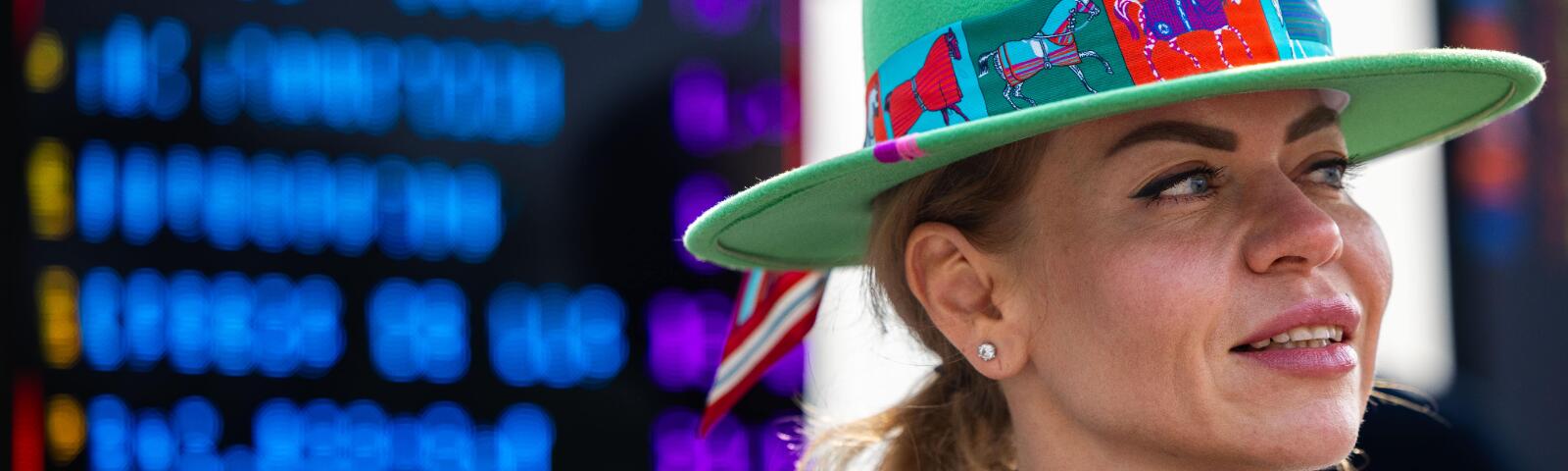 An extreme close up of a race goer at Windsor Races in front of a bookmaker board