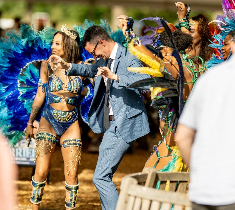A race goer dances with carnival dancers at Windsor Racecourse