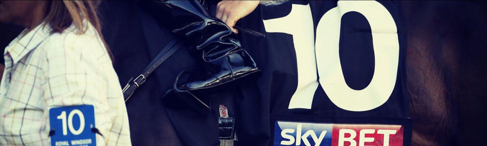 Close up on a jockey on a horse, with a SkyBet branded saddle.