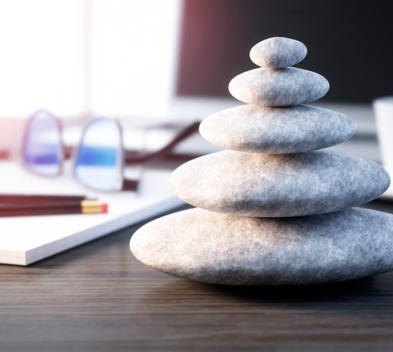 wellness/relaxation stones on desk with notebook, coffee mug, pens and glasses