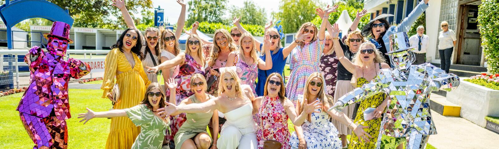 A large hen do party posing in the sunshine on the lawns of Windsor Races